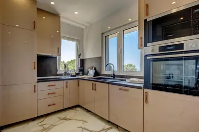 a kitchen with white cabinets and black appliances at Hamburg in Utjeha