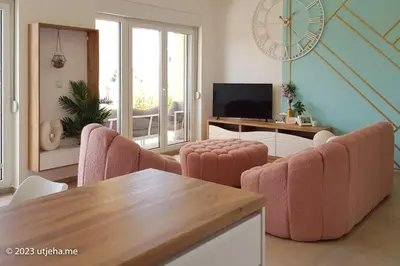 a living room with pink chairs and a table at Sunset Penthouse in Utjeha