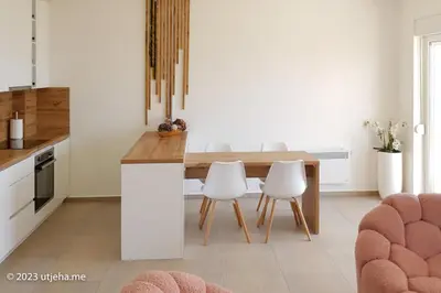 a kitchen with a wooden table and white chairs at Sunset Penthouse in Utjeha