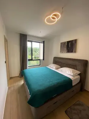 a bedroom with a large bed with a green blanket at Modern 2BR Apt in Rafailovići - Near the Beach in Budva