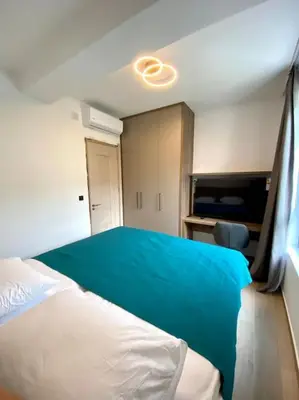 a bedroom with a large bed with a blue blanket at Modern 2BR Apt in Rafailovići - Near the Beach in Budva