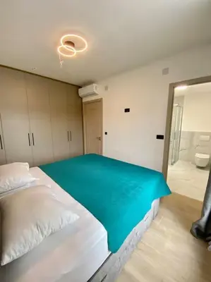 a bedroom with a large white bed and a mirror at Modern 2BR Apt in Rafailovići - Near the Beach in Budva
