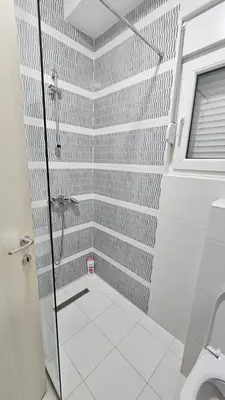 a bathroom with a shower with white tile walls at Lamela B in Podgorica