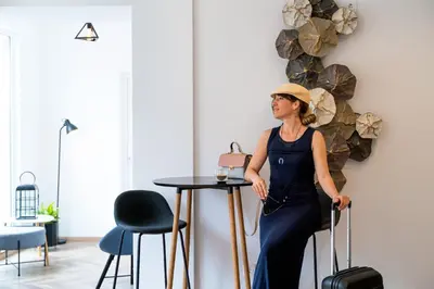 a woman standing next to a table with a suitcase at Sun and Sea Apartments in Budva