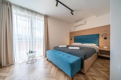 a bedroom with a blue bed and a large window at Sun and Sea Apartments in Budva