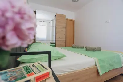 a bedroom with a bed with green sheets and a flower at Top27 in Budva