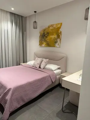 a bedroom with a pink bed and a painting on the wall at Avio Apartments in Podgorica