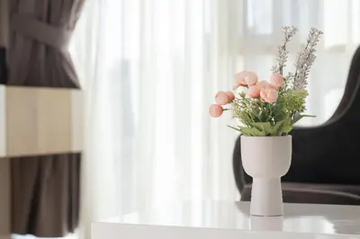a white vase with pink flowers on a table at Tre canne cozy sea view apartment in Budva