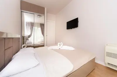 a white bedroom with a bed and a flat screen tv at Tre canne cozy sea view apartment in Budva