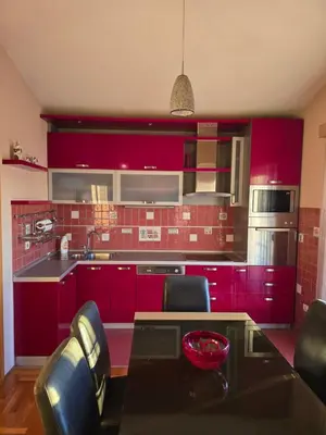 a kitchen with red cabinets and a table with chairs at UnaTea Suites in Bar