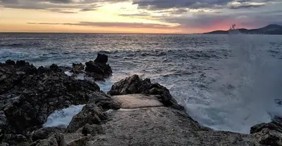 a sunset over the ocean with rocks in the water at Villa Symphony apartments Kotor Tivat in Kotor