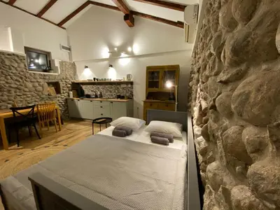 a bedroom with a bed and a stone wall at Cevna River in Podgorica