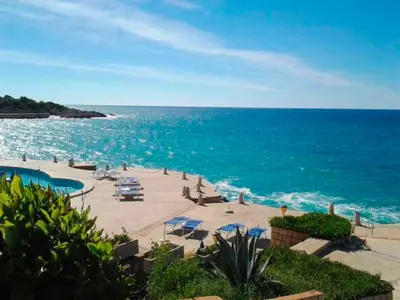 a beach with chairs and umbrellas and the ocean at Villa Blanca in Utjeha