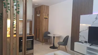 a living room with a table and chairs and a television at Ella Lux Apartment in Podgorica