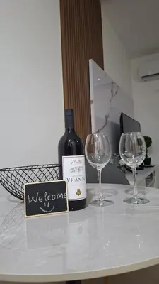 a bottle of wine and two wine glasses on a table at Ella Lux Apartment in Podgorica