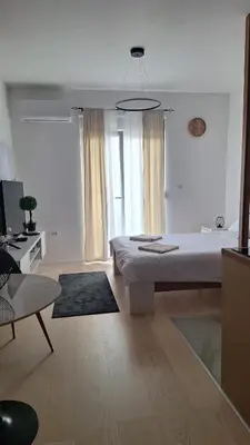 a white room with a bed and a couch and a table at Ella Lux Apartment in Podgorica