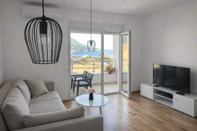 a living room with a couch and a tv and a table at Apartment Jana Meerblick mit Balkon nähe Sandstrand in Becici
