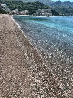 a rocky beach with blue water and buildings in the background at Apartment Jana Meerblick mit Balkon nähe Sandstrand in Becici