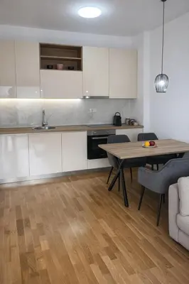 a kitchen with white cabinets and a table and chairs at Apartment Jana Meerblick mit Balkon nähe Sandstrand in Becici
