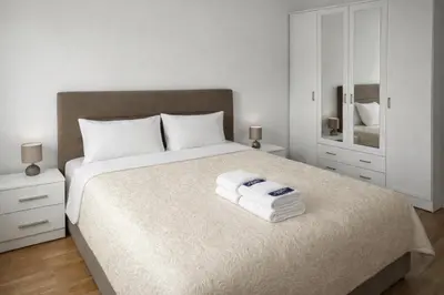 a white bedroom with a large bed with towels on it at Apartment Jana Meerblick mit Balkon nähe Sandstrand in Becici