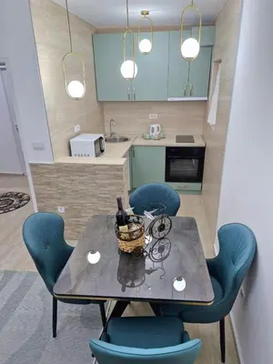 a dining room table with blue chairs and a kitchen at Podgorica Near Big Fashion in Podgorica