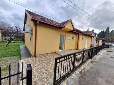 a small yellow house with a black fence at Podgorica Near Big Fashion in Podgorica
