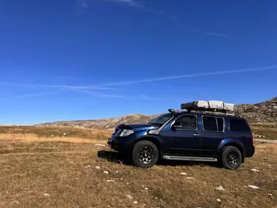 a blue suv parked in a field with a roof rack at Escape Montenegro Campervan Durmitor in Podgorica