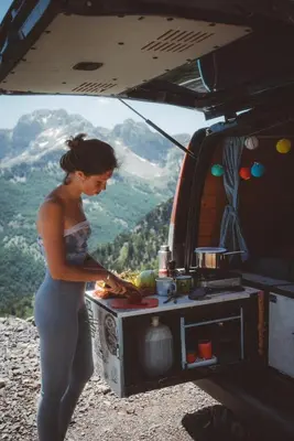 a woman standing next to a food stand on a mountain at Escape Montenegro Campervan Tranzit in Podgorica