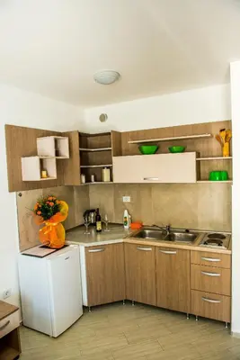 a kitchen with wooden cabinets and a white refrigerator at Apartmani Barović Bečići in Becici