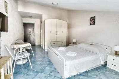 a bedroom with a bed and a table and a chair at Sun Guest House in Budva