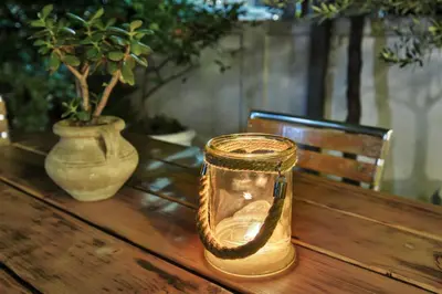 a glass jar sitting on a wooden table with a vase at Sun Guest House in Budva