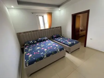 two beds in a bedroom with blue sheets and flowers at Apartments Bettii in Ulcinj
