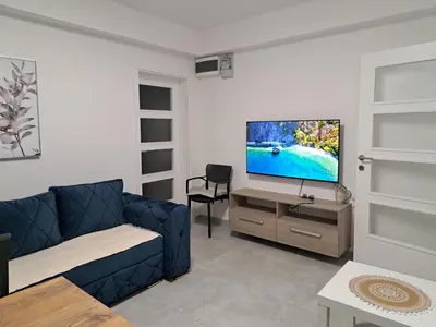 a living room with a blue couch and a flat screen tv at Kali in Budva