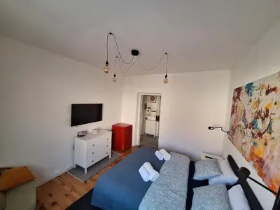 a bedroom with a blue bed and a tv at Cozy City Centar Studio in Podgorica