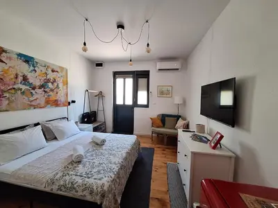 a bedroom with a bed and a living room at Cozy City Centar Studio in Podgorica
