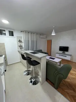 a kitchen and living room with a table and chairs at Apartman Autobuska in Podgorica