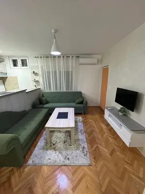 a living room with a green couch and a table at Apartman Autobuska in Podgorica