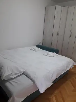 a white bed with two towels on top of it at Apartman Autobuska in Podgorica
