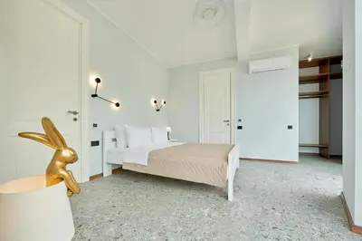 a white bedroom with a bed and a lamp at Панорамная квартира на первой линии моря Skyline Resort, Becici, Budva in Becici