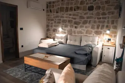 a living room with a couch and a stone wall at Etno House Mali Grm in Bar