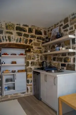 a kitchen with white cabinets and a stone wall at Etno House Mali Grm in Bar