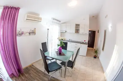 a kitchen and dining room with a table and purple curtains at Villa Nadezda in Petrovac na Moru
