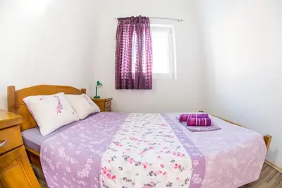 a bedroom with a bed with a purple comforter and a window at Villa Nadezda in Petrovac na Moru