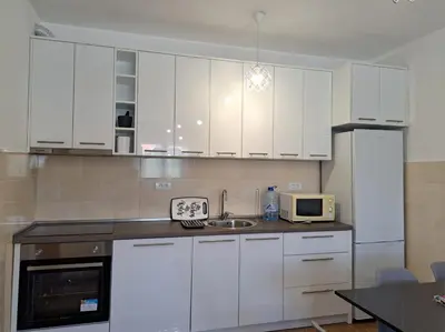 a kitchen with white cabinets and a sink and a microwave at Gruda 086 in Cetinje