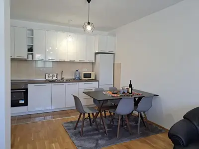 a kitchen with white cabinets and a table and chairs at Gruda 086 in Cetinje