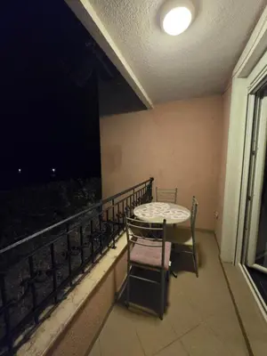 a table and chair on a balcony at night at Jednosoban apartman Anara Prijevor in Budva
