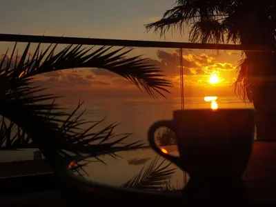 a cup with a candle in front of a window with the sunset at A&N Apartments in Ulcinj
