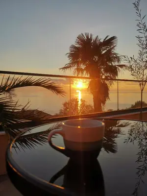 a coffee cup sitting on a table in front of a sunset at A&N Apartments in Ulcinj