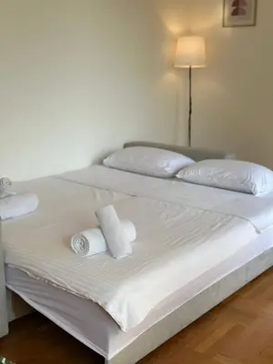 a white bed with two rolled towels on it at Sunny Studio Podgorica in Podgorica
