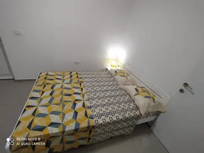 a bedroom with a bed with a yellow and blue quilt at Apartments Nahla in Bar